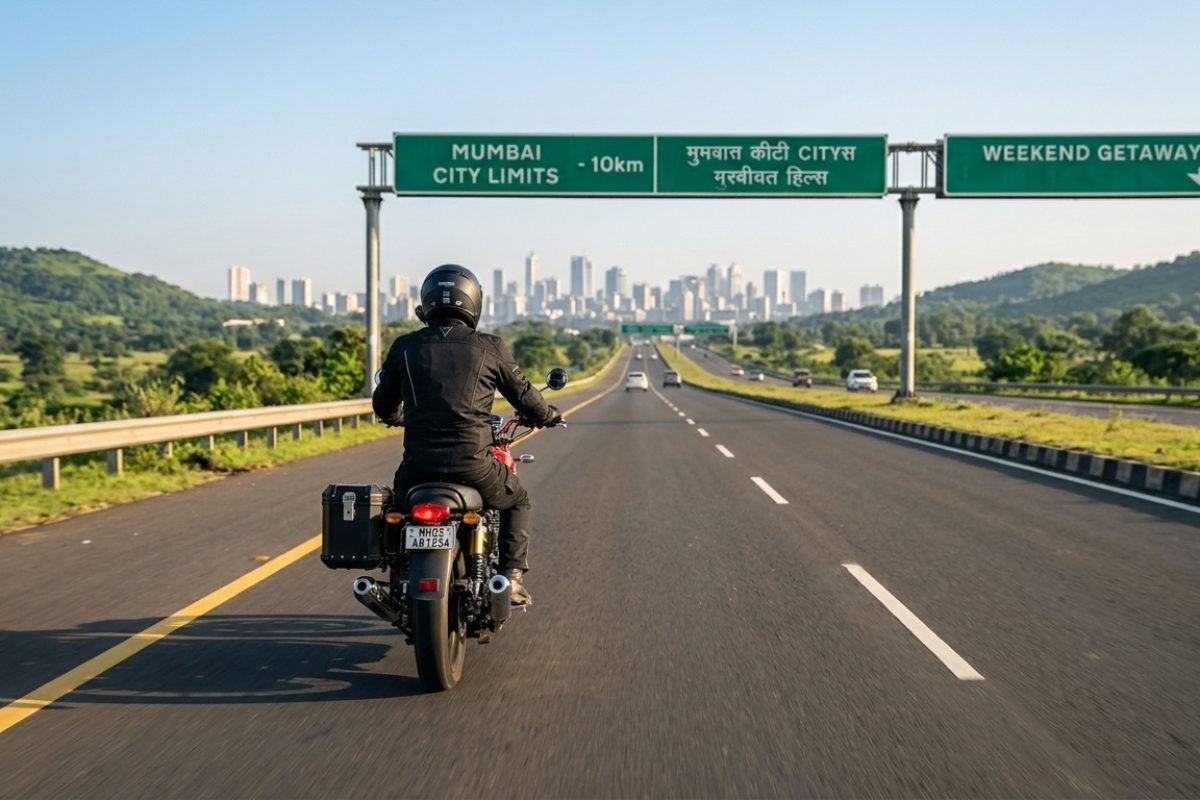 motorcycle rider riding on highway near city with hills and greenery